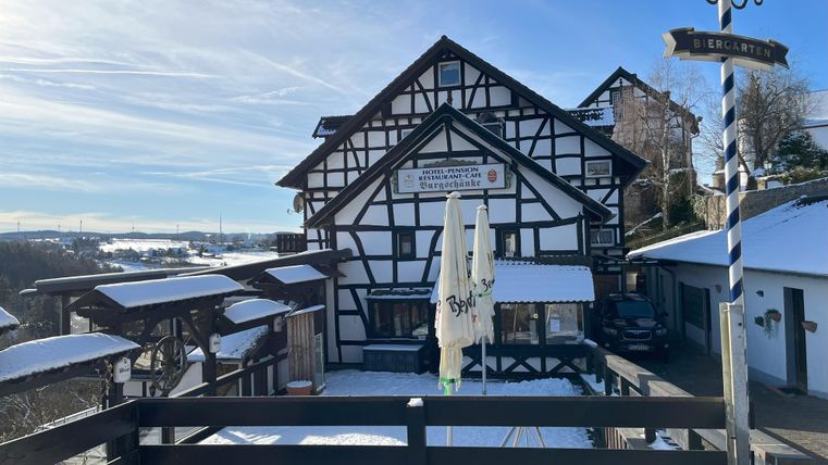 Ein traditionelles Fachwerkhaus im Winter mit Schnee bedeckt. Der Himmel ist klar und blau, und es gibt eine schöne Aussicht auf die Landschaft.