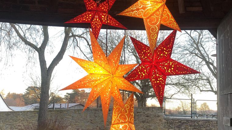 Kleurige sterren van papier hangen decoratief in de lucht. Ze stralen in warme kleuren en creëren een feestelijke sfeer.