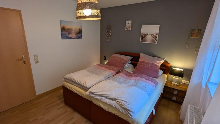 A cozy bedroom with a large double bed and soft colors. A warmly glowing lamp and decorative elements create an inviting atmosphere.