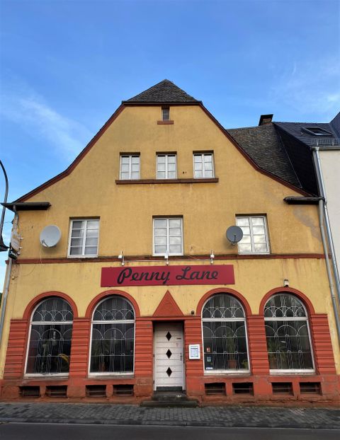 Een historisch gebouw met een gele gevel en rode accenten. Daarop staat de tekst "Penny Lane".