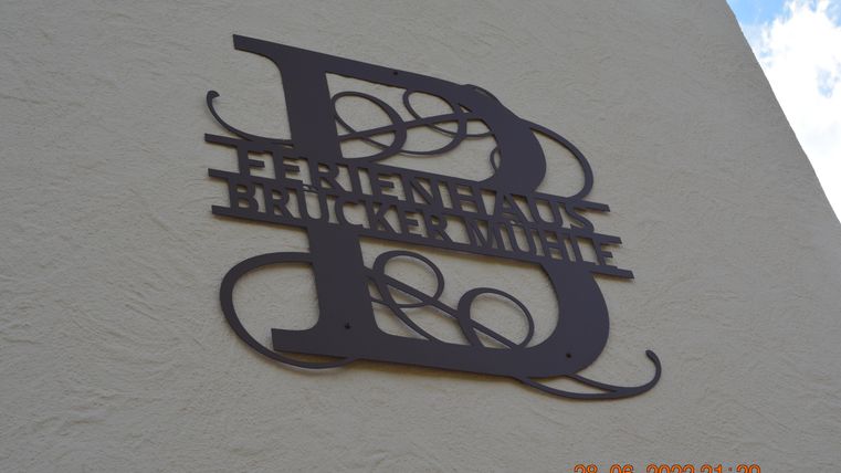 Ein dekoratives Schild mit der Aufschrift "Ferienhaus Brückermühle". Es ist aus Metall gefertigt und an einer Wand angebracht.
