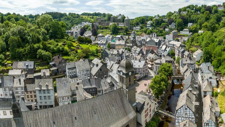 Eine malerische Stadt mit traditionellen Gebäuden und sanften Hügeln. Die Landschaft ist grün und einladend, perfekt für einen ruhigen Spaziergang.