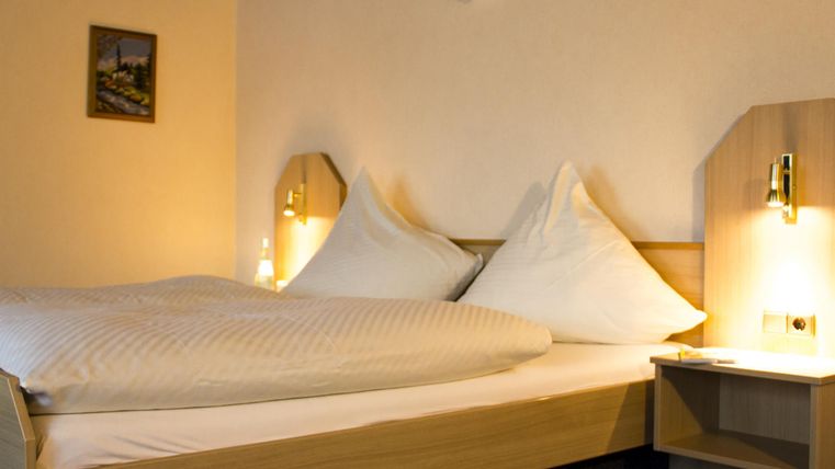 Een gezellige slaapkamer met een tweepersoonsbed en zachte kussens. De zachte verlichting creëert een ontspannen sfeer.