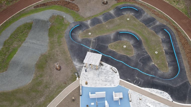 A view of a cut track with various curves and colors. In the foreground, there is a building with a blue roof.