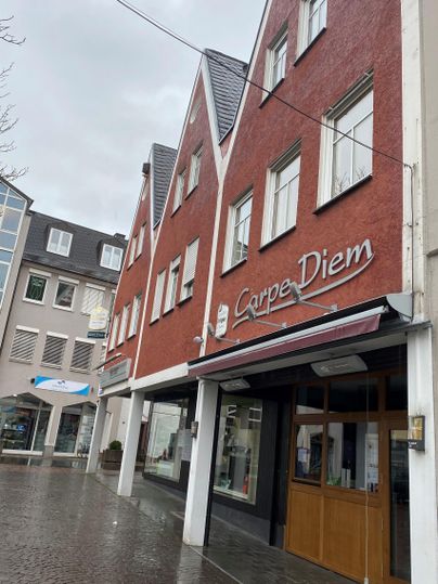 Ein rotes Gebäude mit einem modernen Restaurant-Schild. Es ist bewölkt und die Straße sieht nass aus.