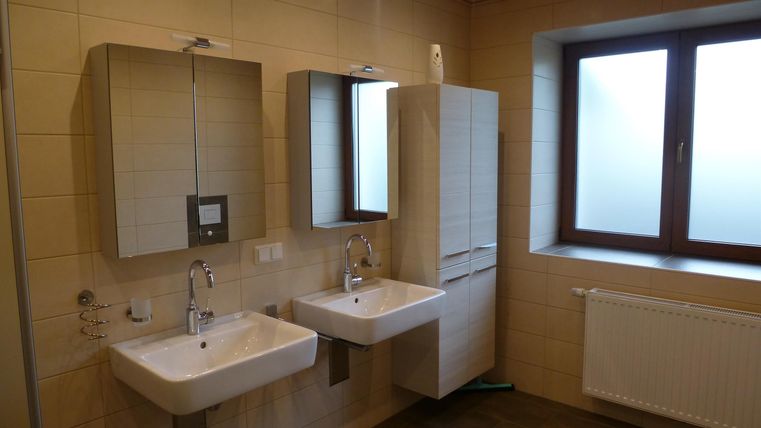 Ein modernes Badezimmer mit zwei Waschbecken und großen Spiegeln. Das Fenster sorgt für natürliches Licht.