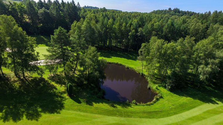 Blick von oben auf Golfanlage mit Teich