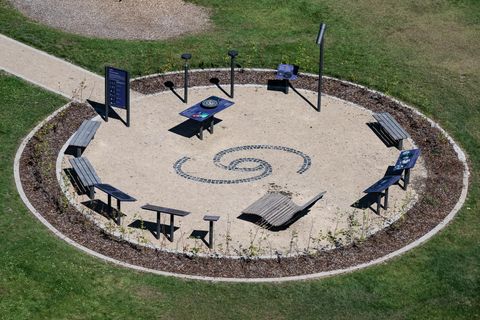 Ein runder Platz mit einem spiralförmigen Muster aus Kies. Mehrere Bänke und Tische laden zum Verweilen ein.