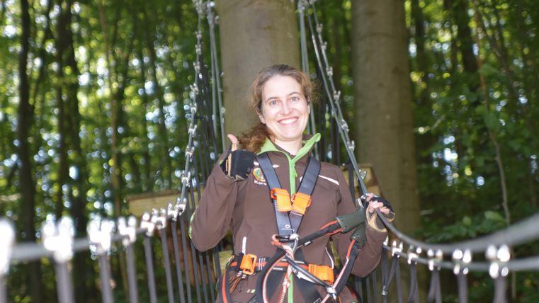 Smiling woman on suspension bridge with zipline