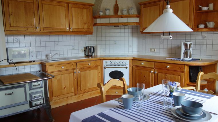 Een gezellige keuken met houten meubels en een lichte werkblad. De tafel is gedekt voor een maaltijd en de sfeer is uitnodigend.