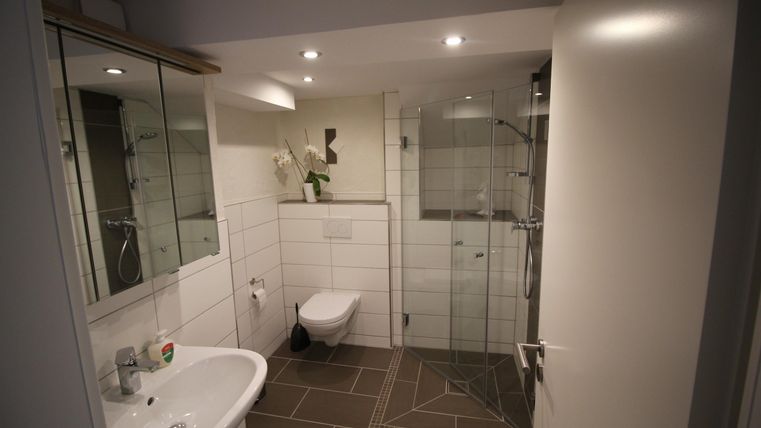 Een moderne badkamer met glazen douche en lichte tegels. De inrichting is minimalistisch en zorgvuldig ontworpen.