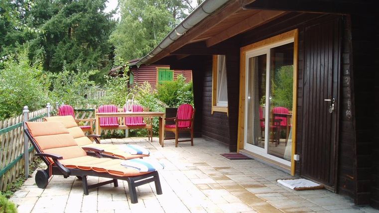 Eine gemütliche Terrasse mit Liegen und einem Esstisch. Umgeben von grünen Bäumen und einem schönen Garten.