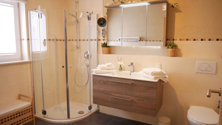 A modern bathroom with a shower and wood design. There are large mirrors and a bright, inviting style.