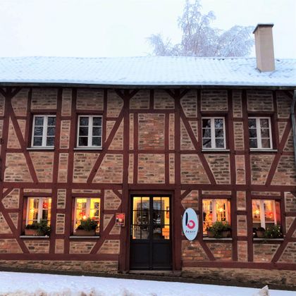 Een oud vakwerkhuis met een rode en bruine gevel. Voor het gebouw ligt sneeuw, en de vensters zijn warm verlicht.