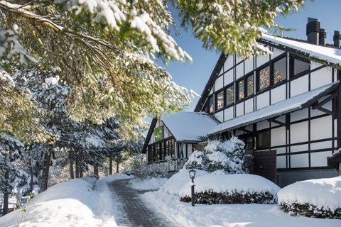 Ein charmantes Haus im Winter, umgeben von Schnee und Bäumen. Der klare Himmel bringt eine friedliche Atmosphäre.