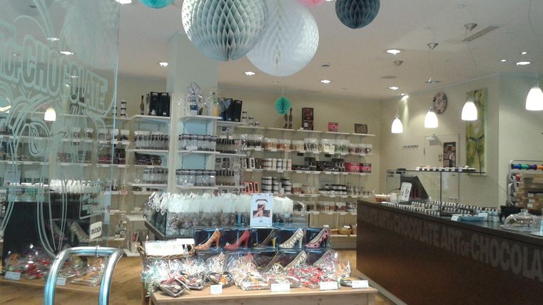 Ein elegantes Schokoladengeschäft mit vielen Leckereien. Desert-Gläser und bunte Dekorationen sorgen für ein einladendes Ambiente.