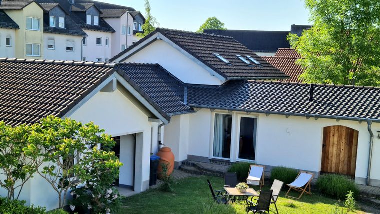 Ein modernes Haus mit einem grünen Garten. Es gibt einen gemütlichen Sitzbereich und eine Terrasse.
