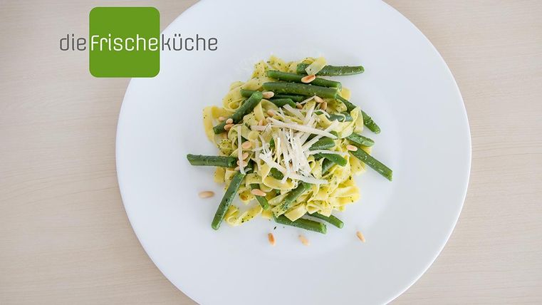 Ein Teller mit Pasta, grünen Bohnen und geriebenem Käse. Das Essen ist ansprechend angerichtet und eignet sich hervorragend für eine gesunde Mahlzeit.