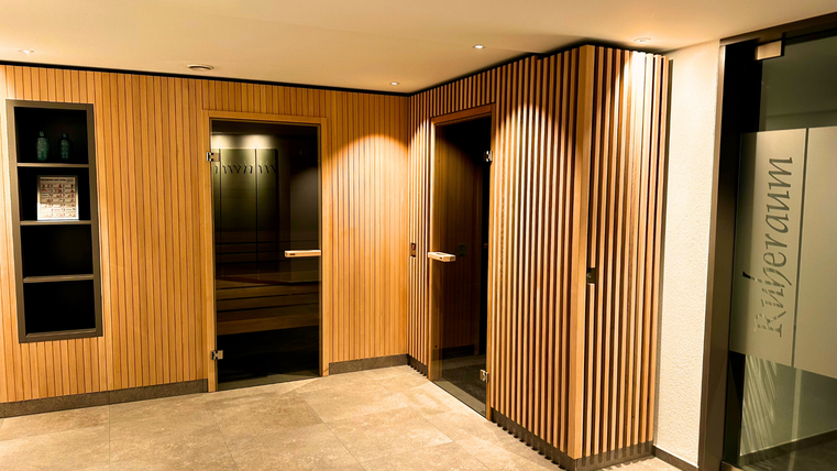 Ein moderner Eingangsbereich mit Holzverkleidung und eleganten Türen. Die Wände sind hell beleuchtet und sorgen für eine einladende Atmosphäre.