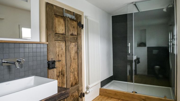 Ein modernes Badezimmer mit einer großen Dusche und einem eleganten Waschbecken. Die Holzdetails verleihen dem Raum eine warme Atmosphäre.