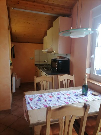 Een gezellige keuken met houten plafonds en lichte muren. Een eetgedeelte met een tafel en stoelen staat op de voorgrond.