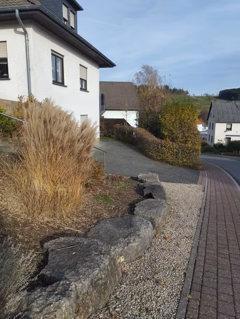 A residential area with a white house and a paved path.