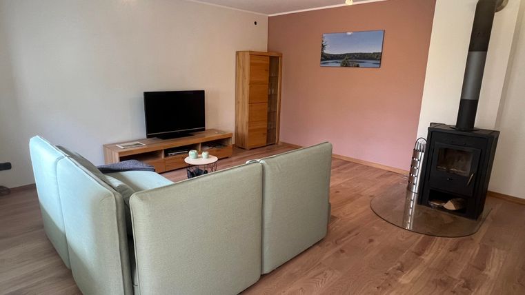 A modernly furnished living room with a cozy sofa and a television. A wooden fireplace provides additional warmth and coziness.