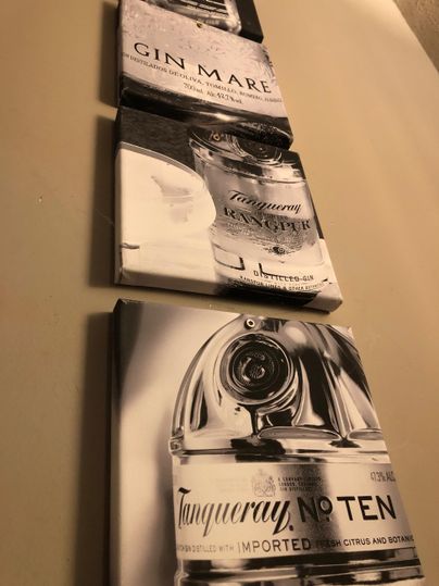 Ein Wandbild mit drei Grafiken von Gin-Flaschen. Die Flaschen sind in schwarz-weiß gehalten und zeigen die Marken Gin Mare und Tanqueray No. Ten.