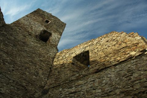 View of the stone walls of the Neublankenheim castle ruins under a blue sky with light clouds.