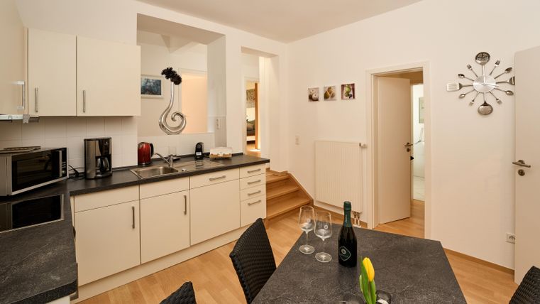 Eine moderne Küche mit hellen Schränken und einer Essecke. Der Raum ist freundlich und einladend, ideal für gesellige Mahlzeiten.