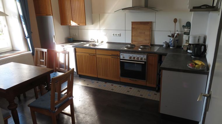 Eine helle Küche mit Holzschränken und modernen Geräten. Ein Esstisch und Stühle ergänzen den Raum.