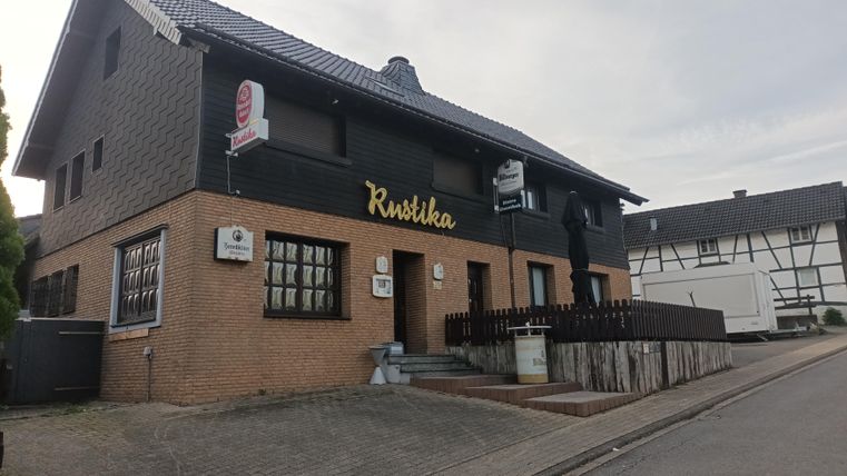 A traditional restaurant in a two-story building with an inviting outdoor area. The facade is made of a mix of brick and dark plaster.