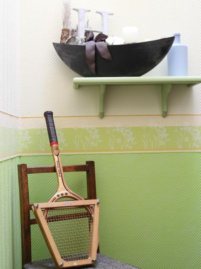 Ein Stuhl mit einem ungewöhnlichen Gegenstand darauf, der an einen Rasenmäher für den Innenbereich erinnert. Im Hintergrund steht eine elegante Schale mit dekorativen Elementen.