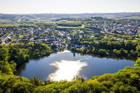 Een schilderachtig landschap met een rustig meer en een kleine stad op de achtergrond. Weelderige groene bomen omringen het water en bieden een vreedzame sfeer.
