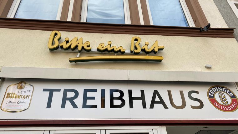 Ein Restaurant mit dem Namen „Treibhaus“ ist zu sehen. Über dem Eingang steht „Bitte ein Bier“.