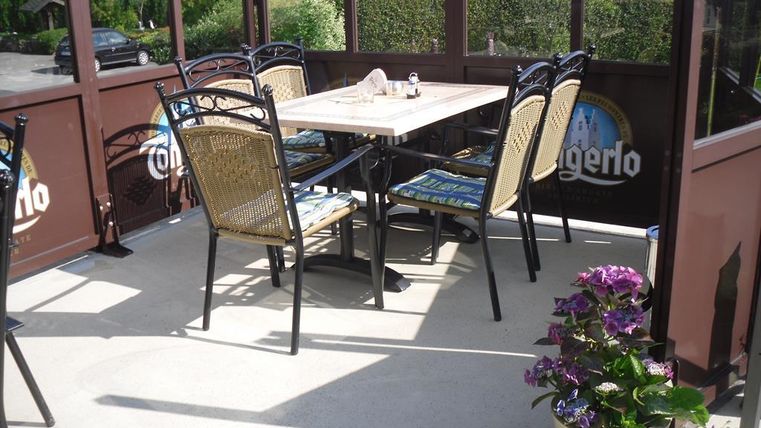 A cozy outdoor area with a table and chairs. Blooming plants create an inviting atmosphere.