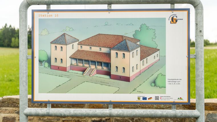 Een bouwtekening van een gebouw met een rood dak en meerdere verdiepingen. De afbeelding toont een gepland gebouw in een groene omgeving.