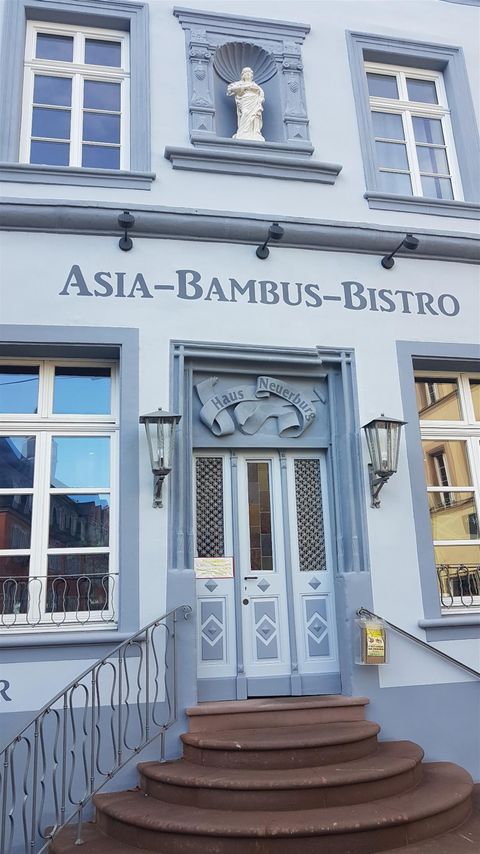 A bistro called "Asia-Bambus-Bistro" with a blue facade. The entrance door features intricate design and steps in front.