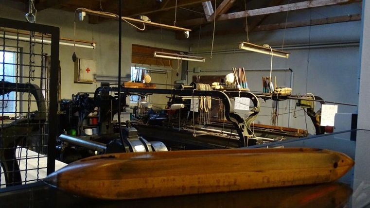 Eine alte Werkstatt mit Maschinen und Werkzeugen. Im Vordergrund liegt ein Holzgegenstand.