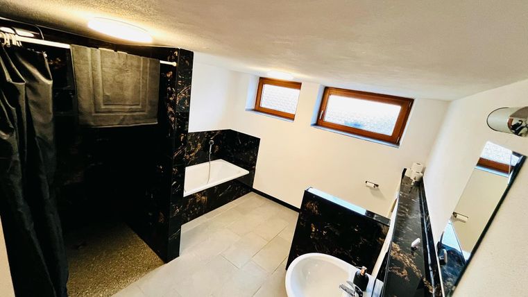 A modern bathroom with a shower and a bathtub. Bright walls and windows create a pleasant light atmosphere.