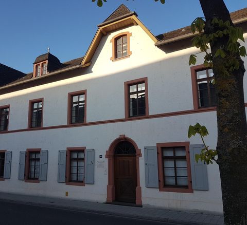 Ein charmantes, historisches Gebäude mit weißen Wänden und roten Akzenten. Die Fenster sind von blauen Fensterläden umrahmt.