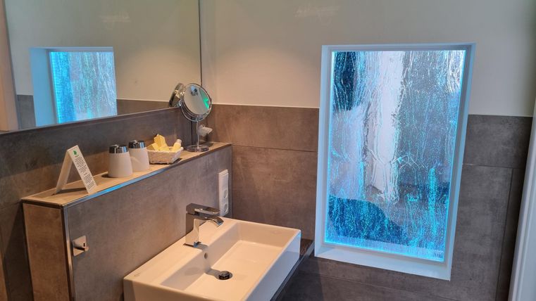 A modern bathroom with a simple sink and a large window. The room feels bright and inviting.