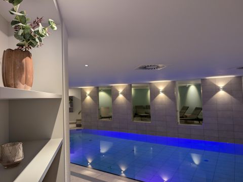 An indoor pool with blue water in a warmly lit spa room.