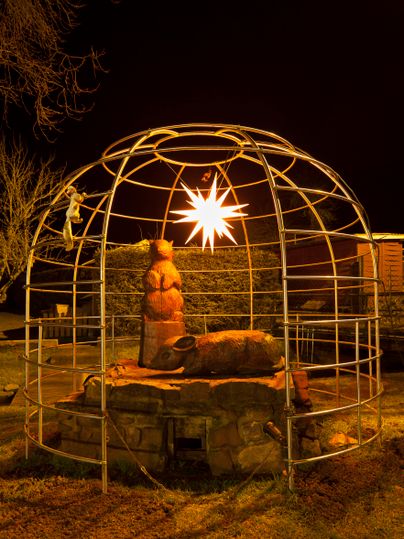 Eine kunstvolle Lichtinstallation in einem abgerundeten Rahmen, die einen Bären darstellt. Der Stern leuchtet in der Dunkelheit und schafft eine festliche Atmosphäre.