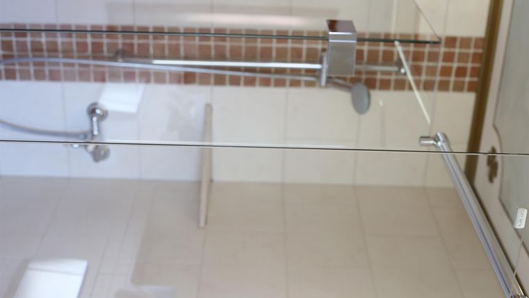 Ein modernes Badezimmer mit einer Glassch shower und neutralen Kacheln. Die Kombination aus weißen und braunen Farben sorgt für eine helle Atmosphäre.