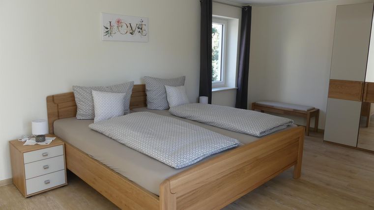 Ein modernes Schlafzimmer mit zwei Betten aus Holz. Die Wände sind hell und die Einrichtung ist freundlich und minimalistisch.