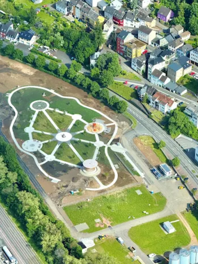 De afbeelding toont een vogelperspectief van een opnieuw ontworpen park met paden, zithoeken en een speeltuin. Daarnaast zijn woonhuizen en groene ruimtes te zien.