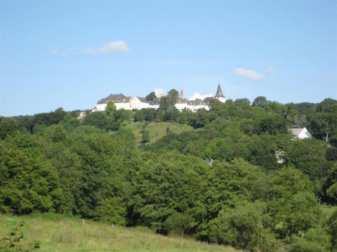 A picturesque village on a hill, surrounded by lush greenery. The blue sky in the background creates an idyllic atmosphere.