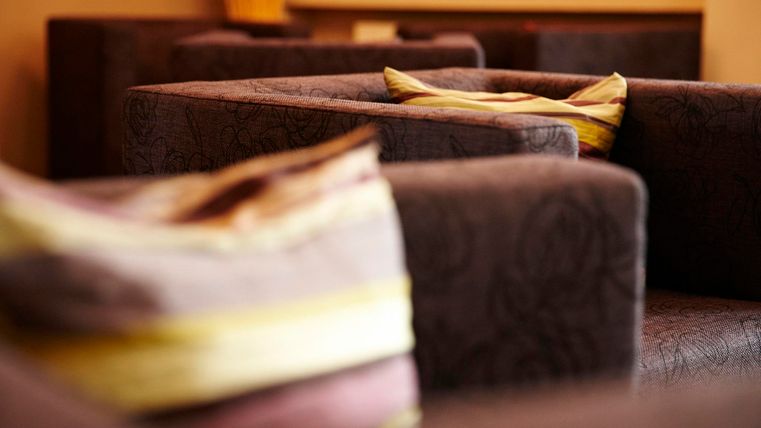 Cozy armchairs with decorative cushions in a warm, inviting room. The gentle lighting creates a relaxed atmosphere.