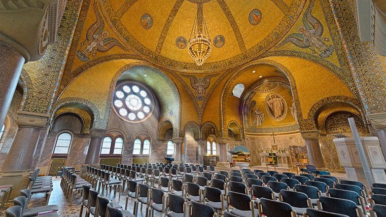 Prachtig interieur van de Verlosserkerk Gerolstein met gouden mozaïeken, engelafbeeldingen en een grote kroonluchter onder een koepel.